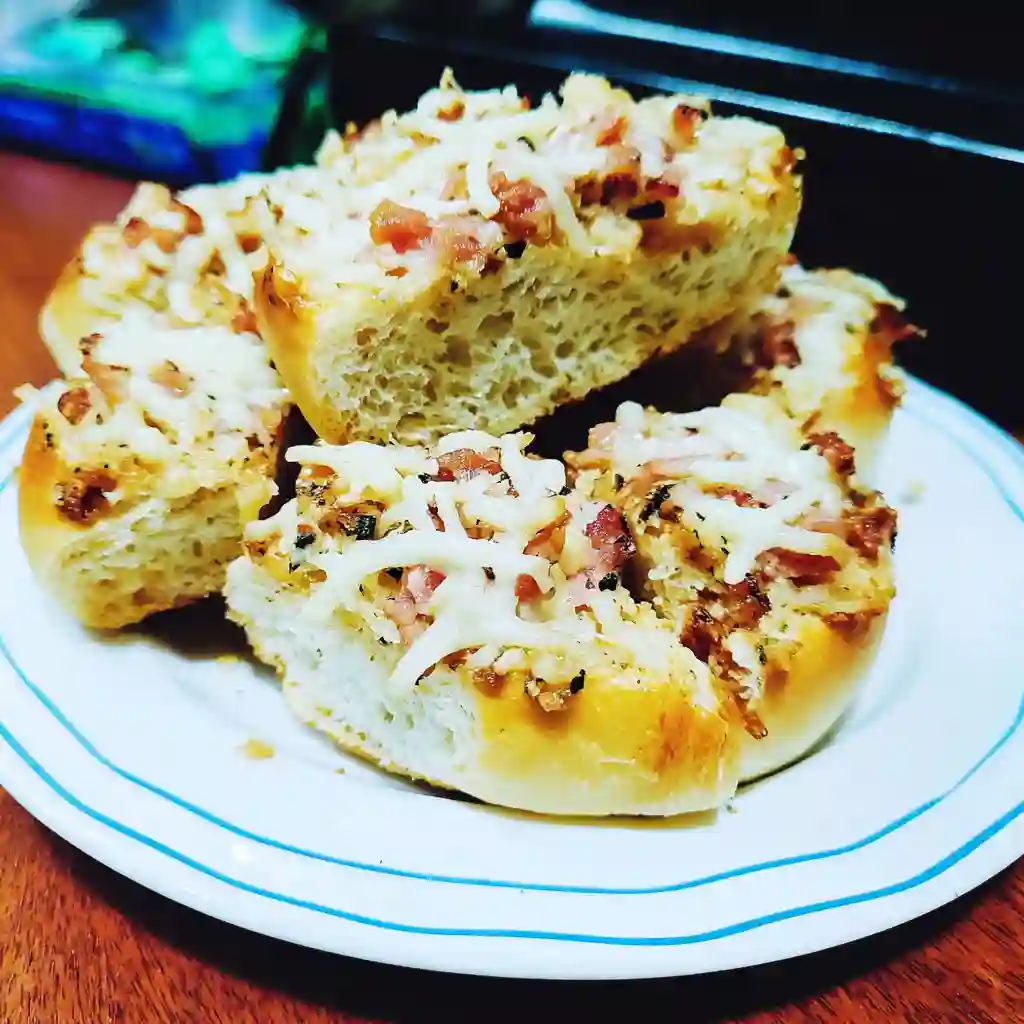 Chicken Bacon Ranch stuffed bread on a white plate golden, cheesy bread pieces filled with chicken, crispy bacon, and creamy ranch sauce, garnished with herbs.