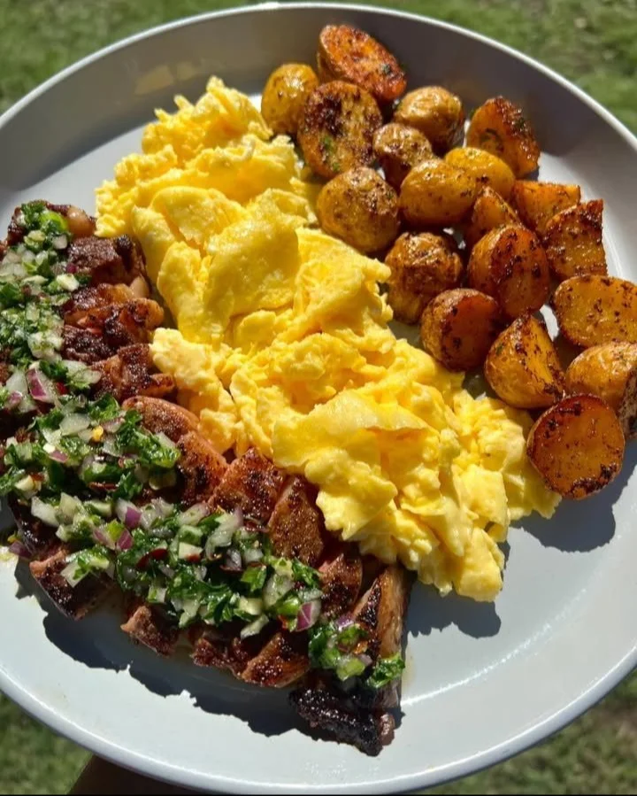 Delicious steak with chimichurri sauce, eggs, and crispy potatoes on a plate.