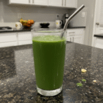 A vibrant green spinach banana smoothie in a tall glass with a straw, garnished with a fresh banana slice. This is a refreshing and healthy Spinach Banana Smoothie.